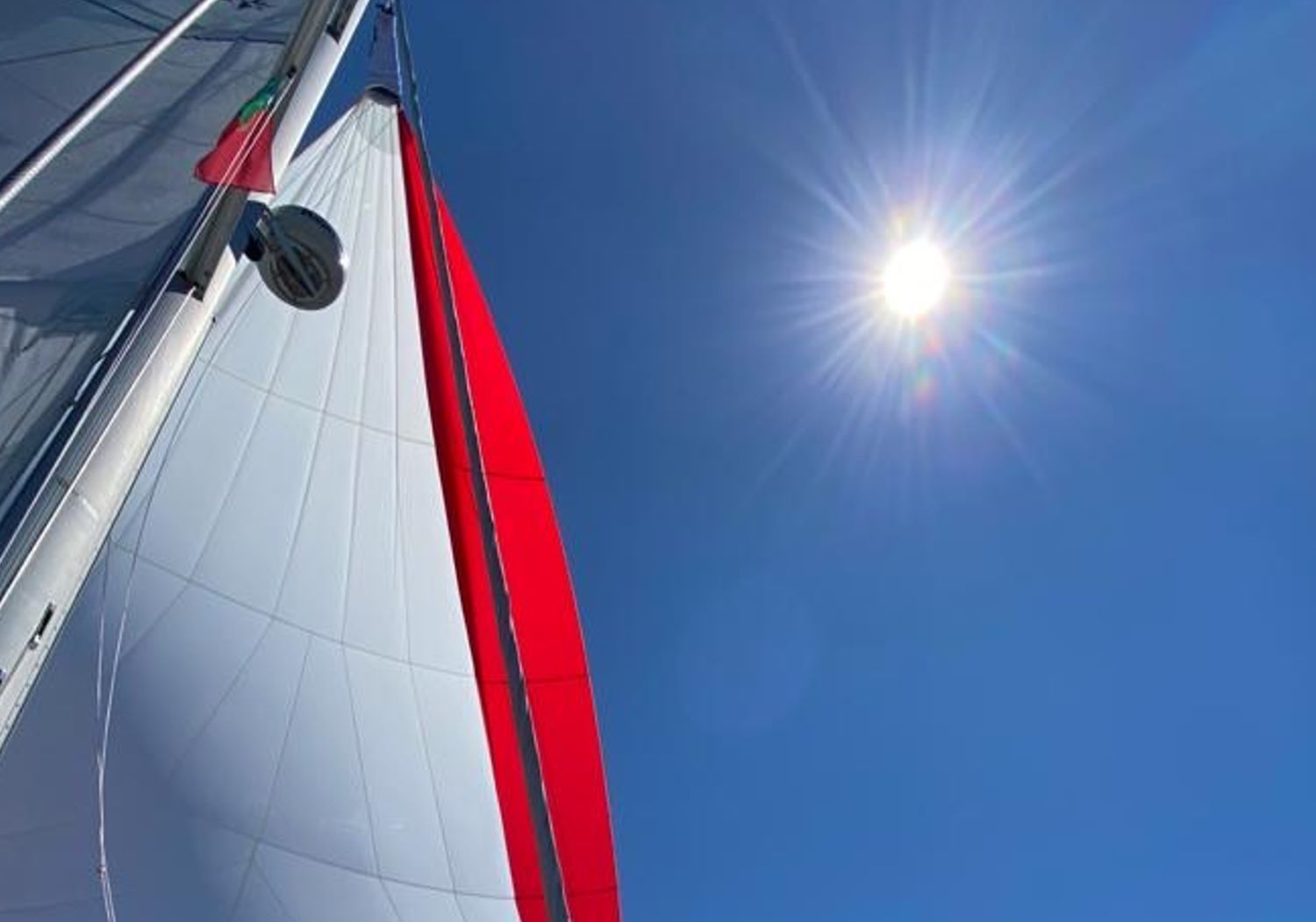 Navegar a vela bajo el sol del Mediterráneo Vela del barco izada navegando bajo un cielo despejado y sol brillante en la Costa Blanca