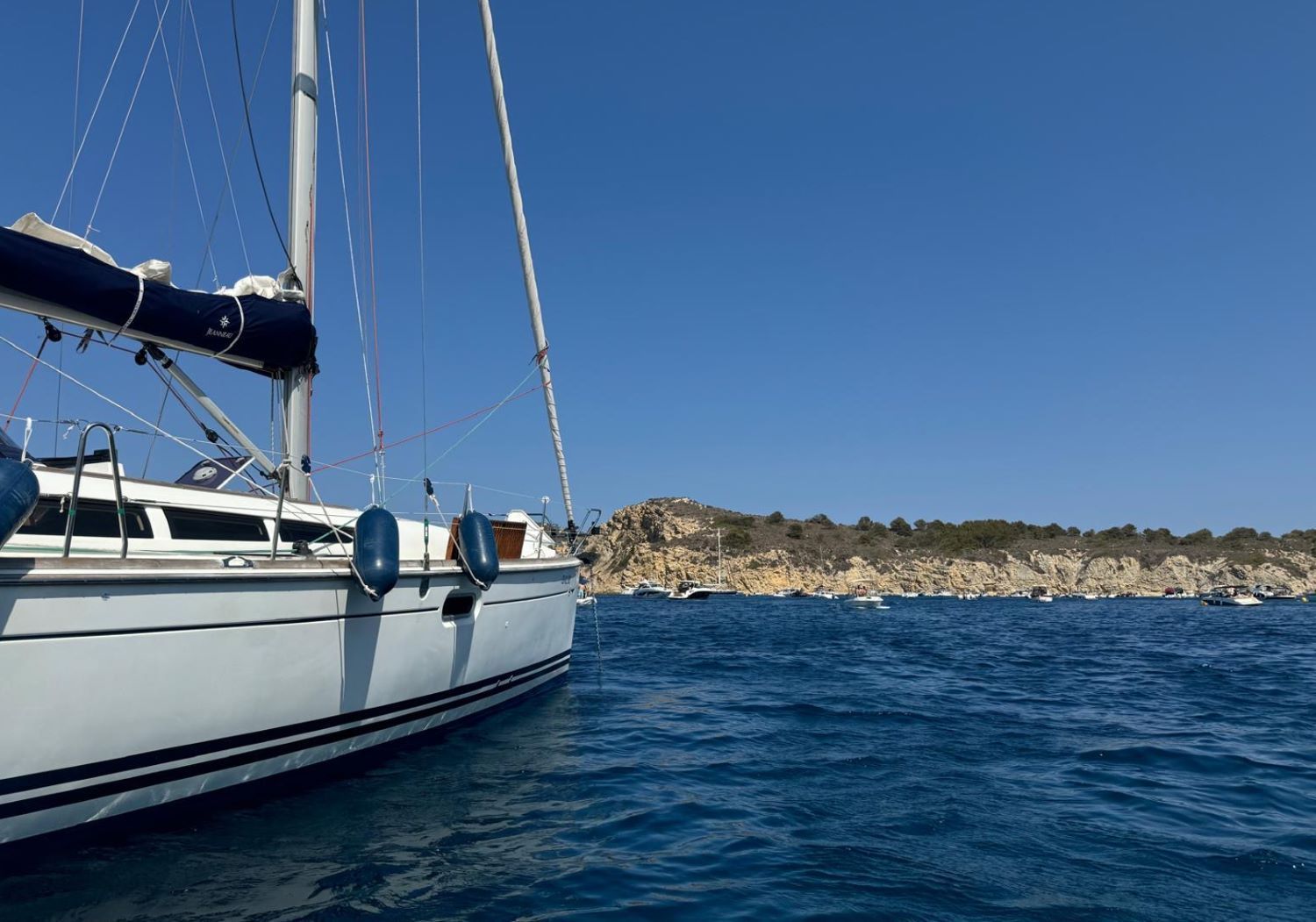 Fondeo en cala tranquila Velero fondeado en aguas tranquilas junto a una cala rocosa en la Costa Blanca.
