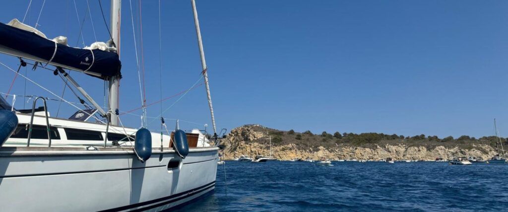 Fondeo en cala tranquila Velero fondeado en aguas tranquilas junto a una cala rocosa en la Costa Blanca.