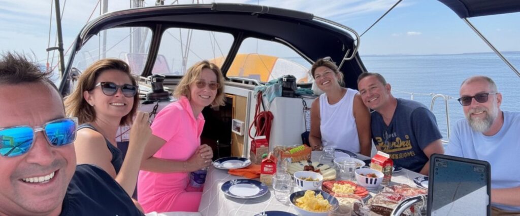Momento de descanso en el velero Grupo de amigos disfrutando de una comida en la cubierta de un velero durante una navegación tranquila en la Costa Blanca.