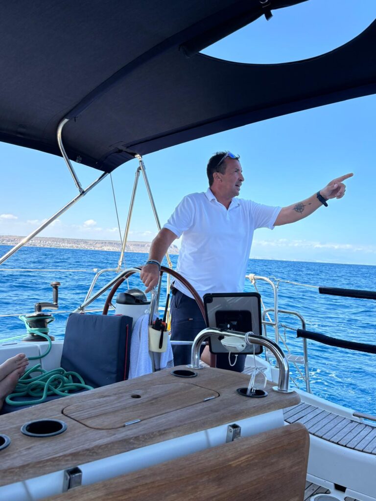 Explicación inicial de seguridad antes de zarpar Patrón señalando y explicando las indicaciones de seguridad a bordo de un velero en un día de mar tranquilo.